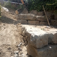 Construcció de mur de contenció de rocalla amb funció de jardinera