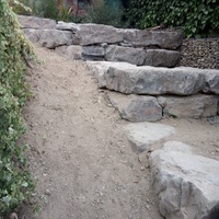 Construcció de mur de contenció de rocalla amb funció de jardinera