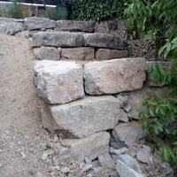 Construcció de mur de contenció de rocalla amb funció de jardinera