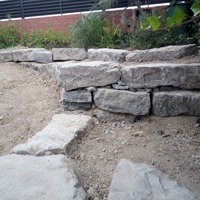 Construcció de mur de contenció de rocalla amb funció de jardinera