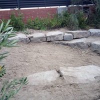 Construcció de mur de contenció de rocalla amb funció de jardinera