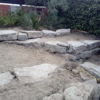 Construcció de mur de contenció de rocalla amb funció de jardinera