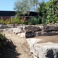 Construcció de mur de contenció de rocalla amb funció de jardinera