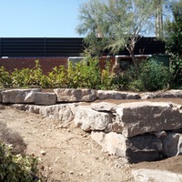 Construcció de mur de contenció de rocalla amb funció de jardinera