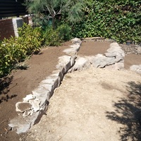 Construcció de mur de contenció de rocalla amb funció de jardinera