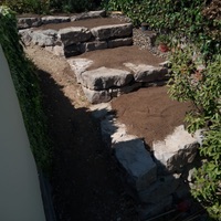 Construcció de mur de contenció de rocalla amb funció de jardinera